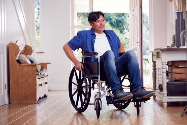 Older asian man in wheelchair inside his home