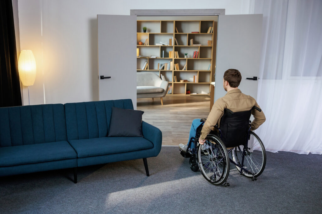 A handsome young man in a wheelchair moves around the apartment, getting used to a new life. Recovery after injury or ill lonely at home